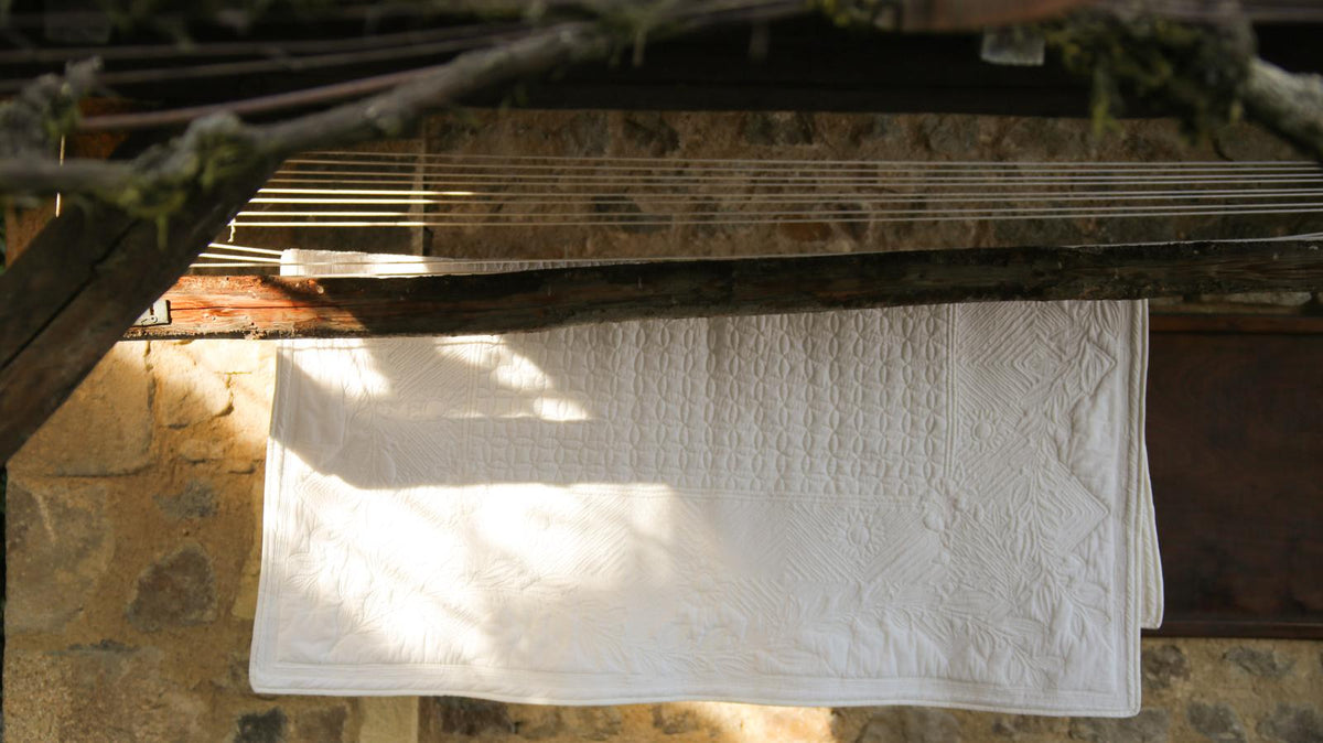 Serviette blanche accrochée à un linge-étendoir sous une terrasse en pierre en plein air.