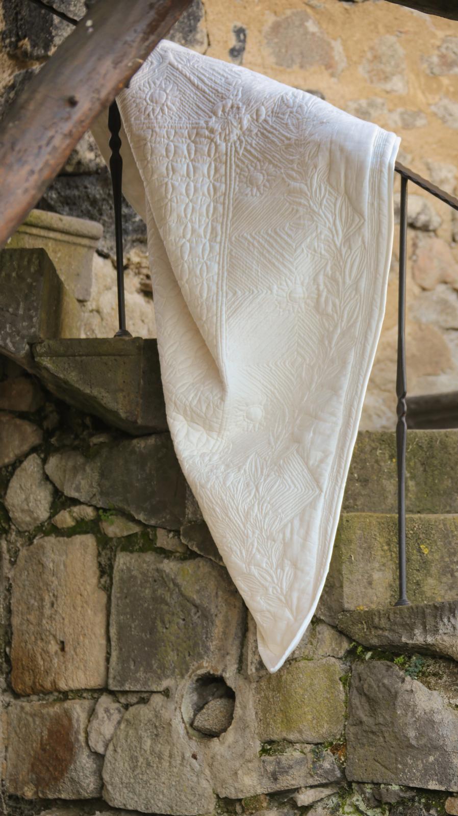Serviette blanche délicatement drapée sur un balcon en pierre, motifs géométriques et reliefs visibles.