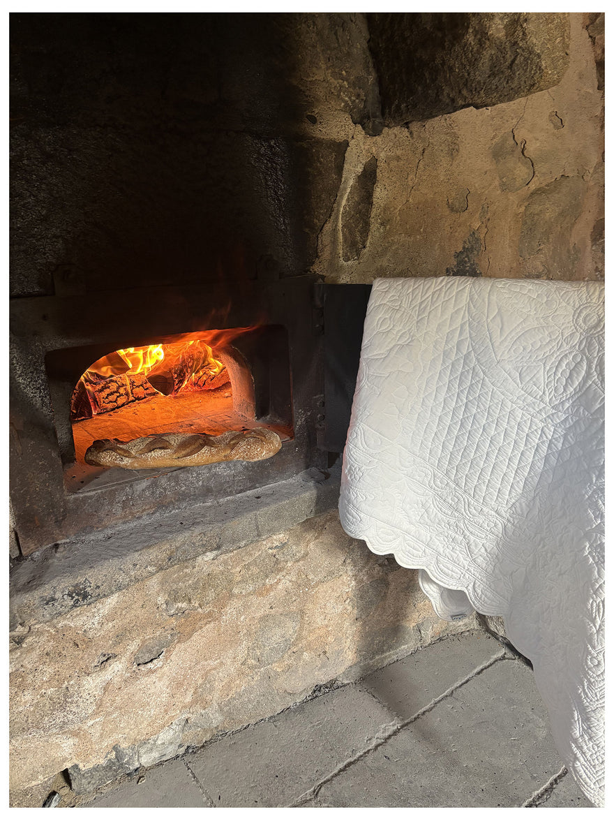 Pain cuit au four à bois dans une stone oven, bread posé près de couverture blanche sur pierre. Le texte “Le carré de mariage Petite France” apparaît en haut.