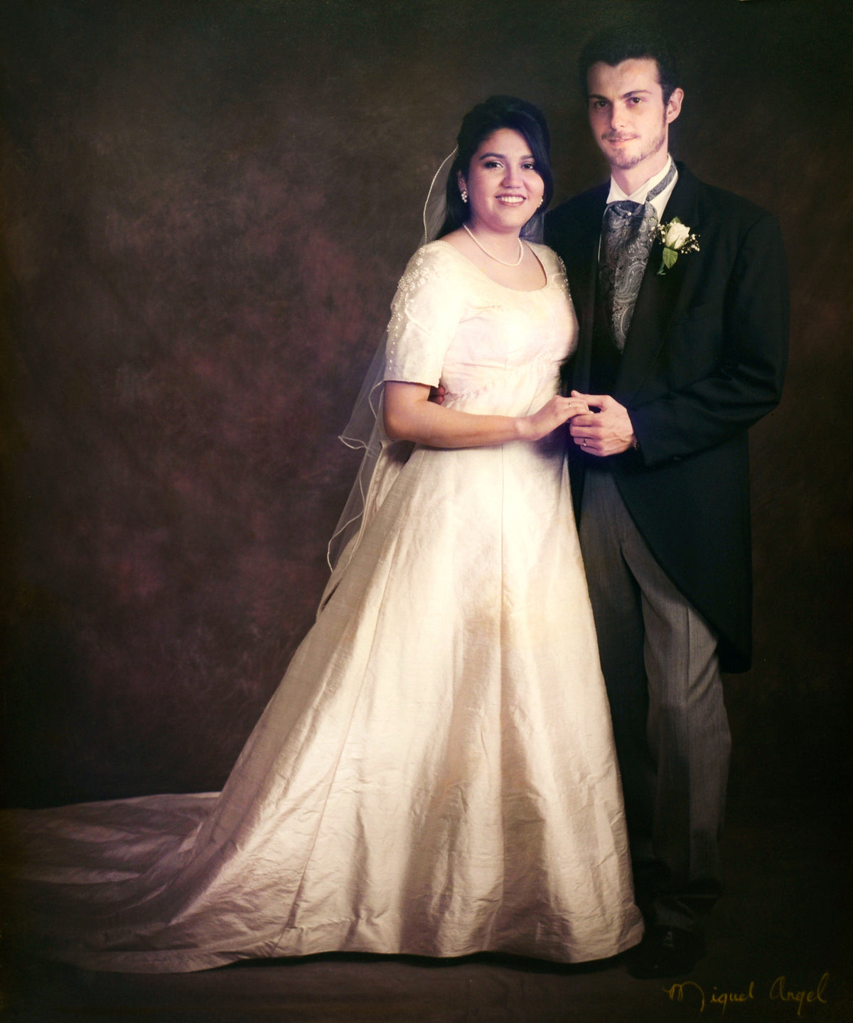 Portrait de mariés en robe de mariée et smoking, se tenant la main, fond brun. Alt text optimisée pour SEO avec le mot-clé éventuel intégré si présent.