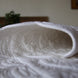 Drap housse blanc matelassé plié, textures quiltées visibles et conforment sur une table.