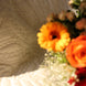 Bouquet de fleurs aux couleurs orange et rouge posé sur un drap clair texturé.