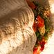 Arrière-plan floral au milieu d’une couette blanche à motifs, avec bouquet de roses orange et autres fleurs blanches et rouges éclairé par une lumière chaude.