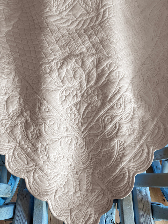 Détailles sur une nappe blanche damassée avec motif floral et organique, posé sur une table bleue en bois.