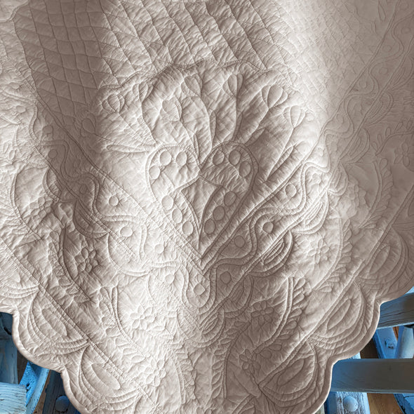 Détailles sur une nappe blanche damassée avec motif floral et organique, posé sur une table bleue en bois.