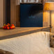 Livré dans un intérieur cosy: un grand livre bleu sombre posé sur une tablette, près d’une lampe, et un petit plat de tomates cerises sur le bois, canapé beige et couverture blanche en tissage.