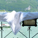 Charmant drapé blanc posé sur une balustrade près d’un lac alpin, avec le panneau “Pont des Amours” en arrière-plan.
