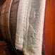 Roue de barrique en bois avec une étoffe ou nappe quiltée blanche drapée sur le côté, bordure dentelée.