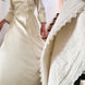 Personne en robe de mariée ivoire, haut ajusté et manches trois quarts, descend les marches près d’une table ornée d’un linge blanc à dentelle.
